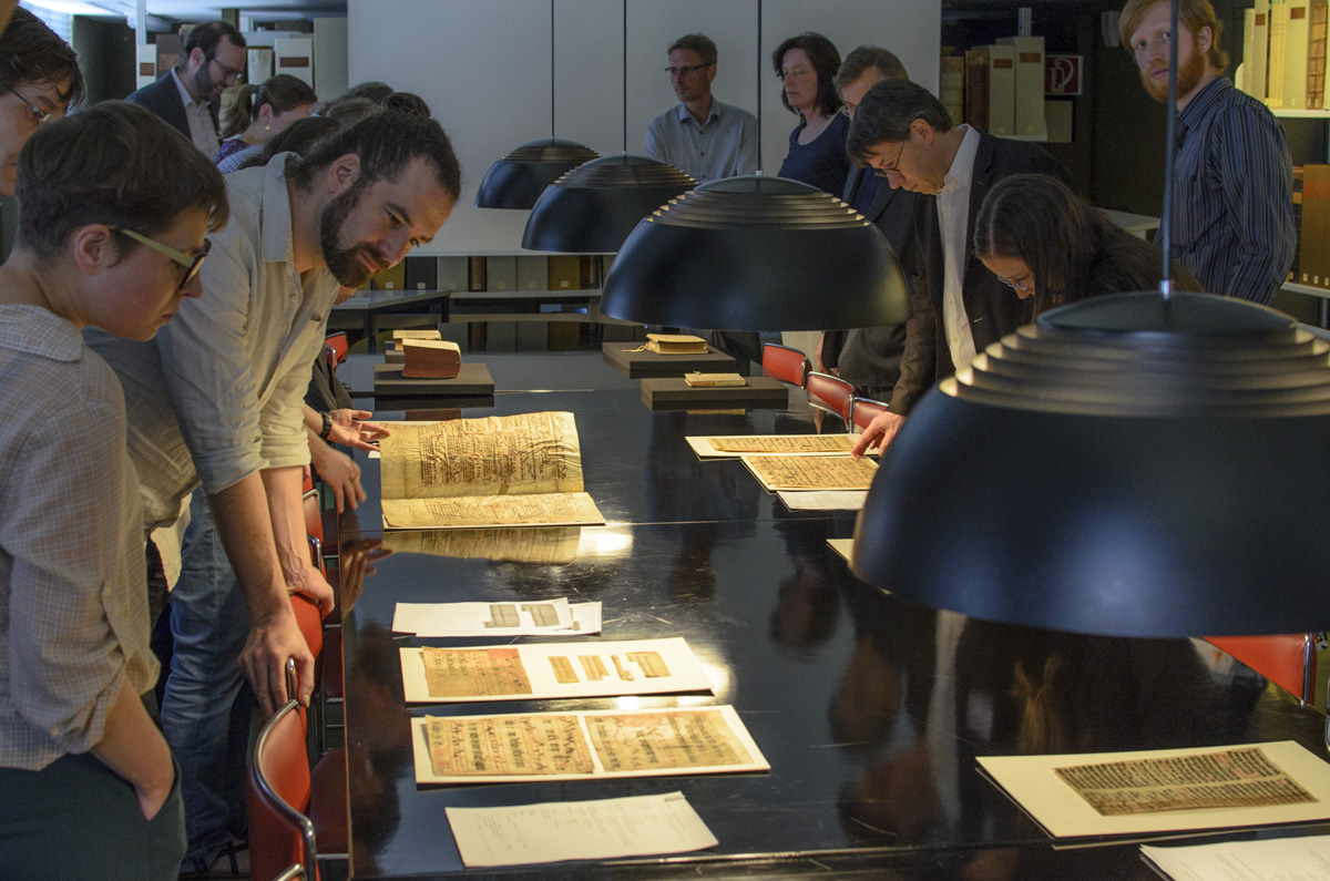 Fragmentologists walking around a table, admiring the HAB Wolfenbüttel's collection of loose fragments.